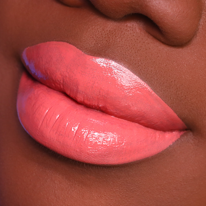 Dreamy coral nude lipstick on lips, deep skin tone close-up