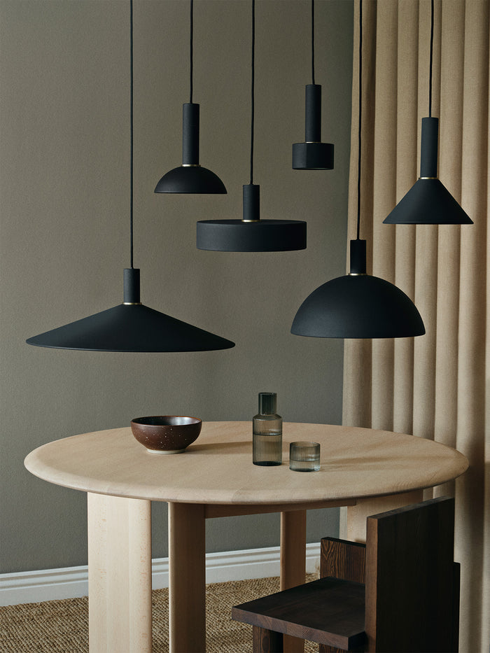 Group of black socket pendants with dome, cone and disc shades over a round dining table
