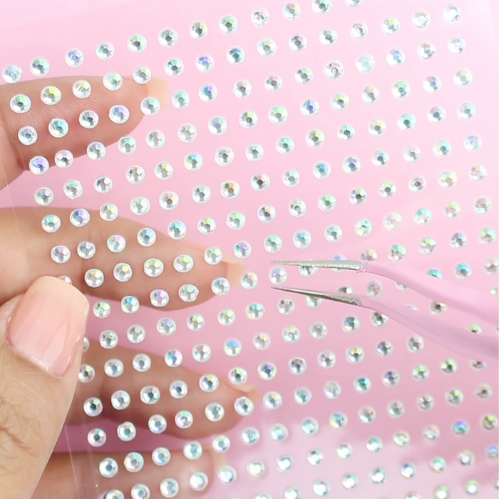 Using the pink tweezer to lift a rhinestone from a decal sheet