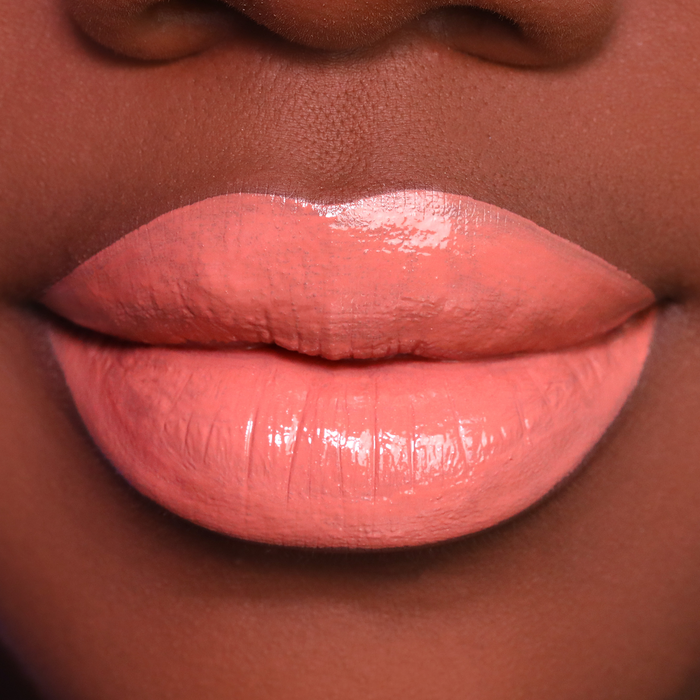 Twisted peachy coral lipstick on lips, medium-deep skin tone
